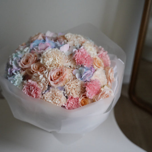 Bouquet of pastel-colored flowers in a clear plastic wrap on a white surface.