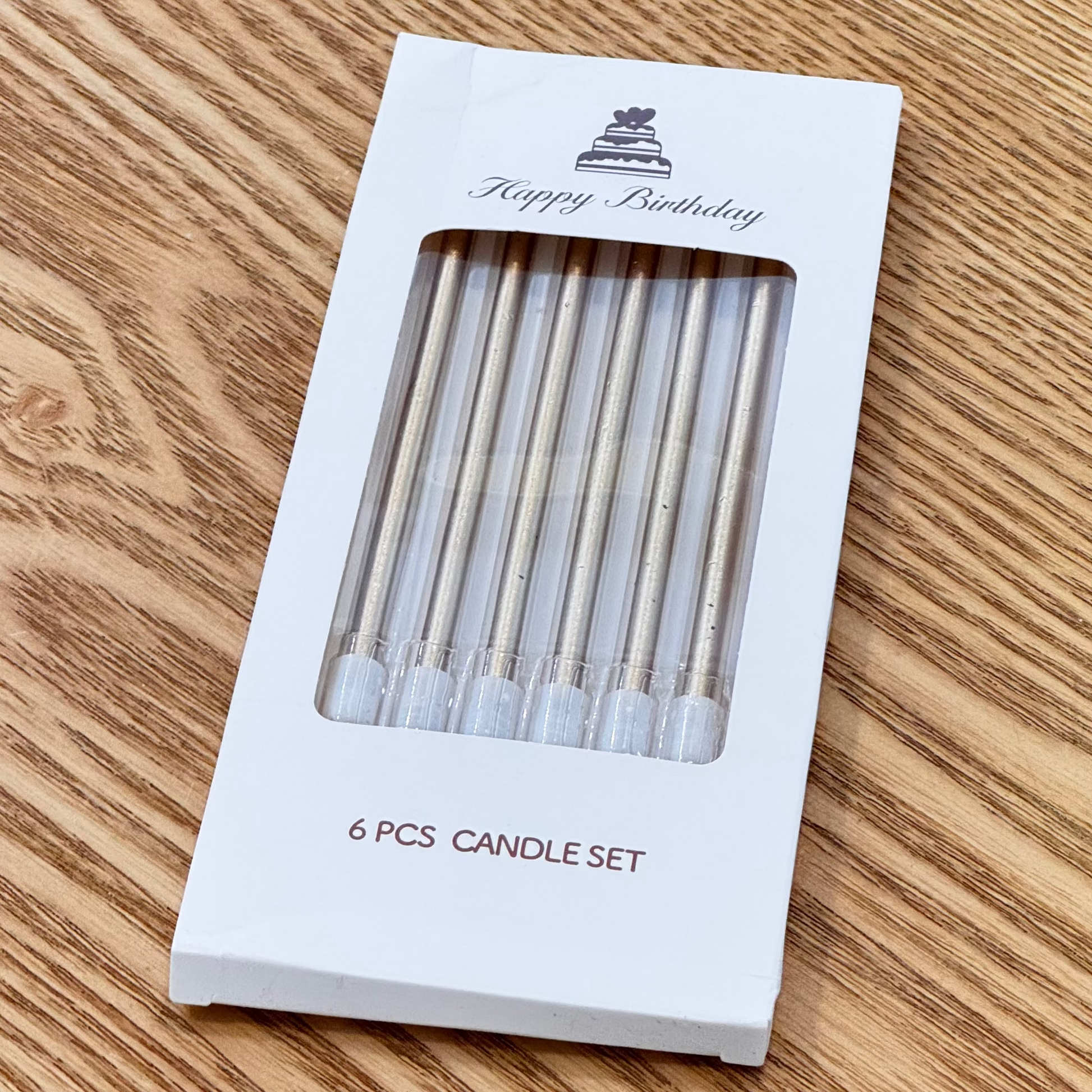 Packaged set of candles with a visible brand logo on a wooden surface