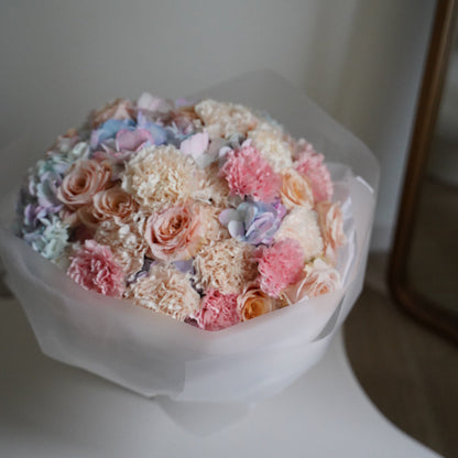 Bouquet of pastel-colored flowers in a clear plastic wrap on a white surface.