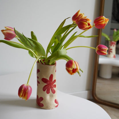 Pink tulips in a vase with floral pattern on a white background