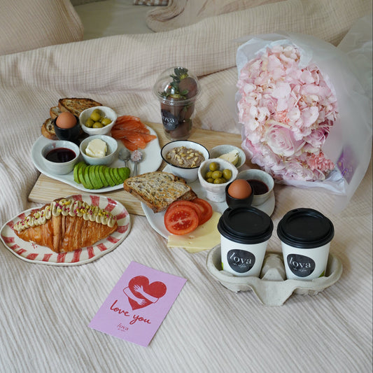 Breakfast in bed set with croissants salmon avocado coffee and pink flower bouquet, romantic morning delivery Lisbon