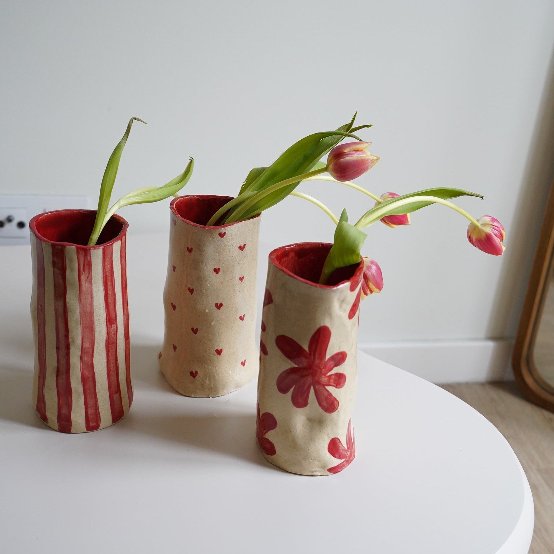 Three small ceramic vases with floral designs on a white surface.