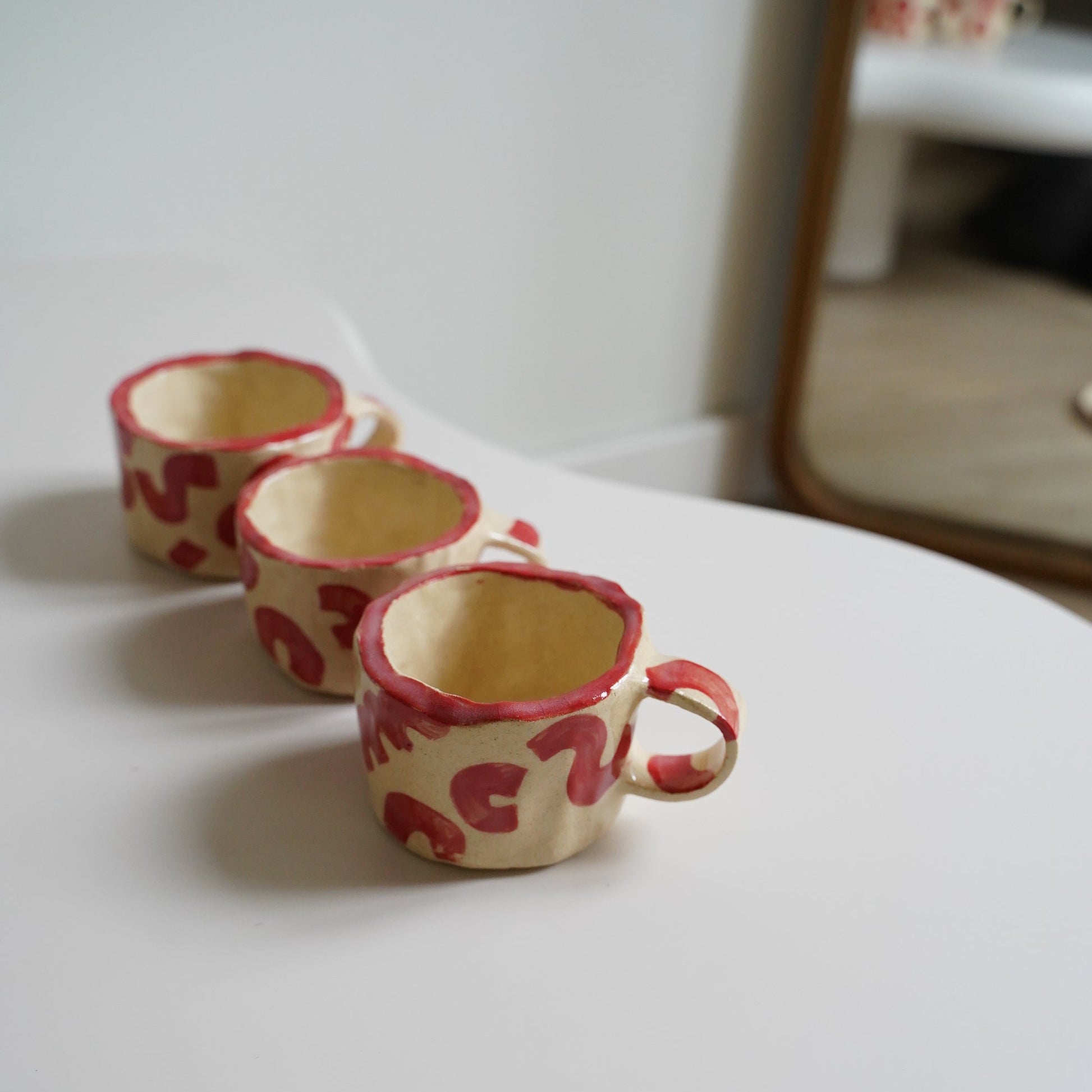 Two decorative cups with red patterns on a white surface