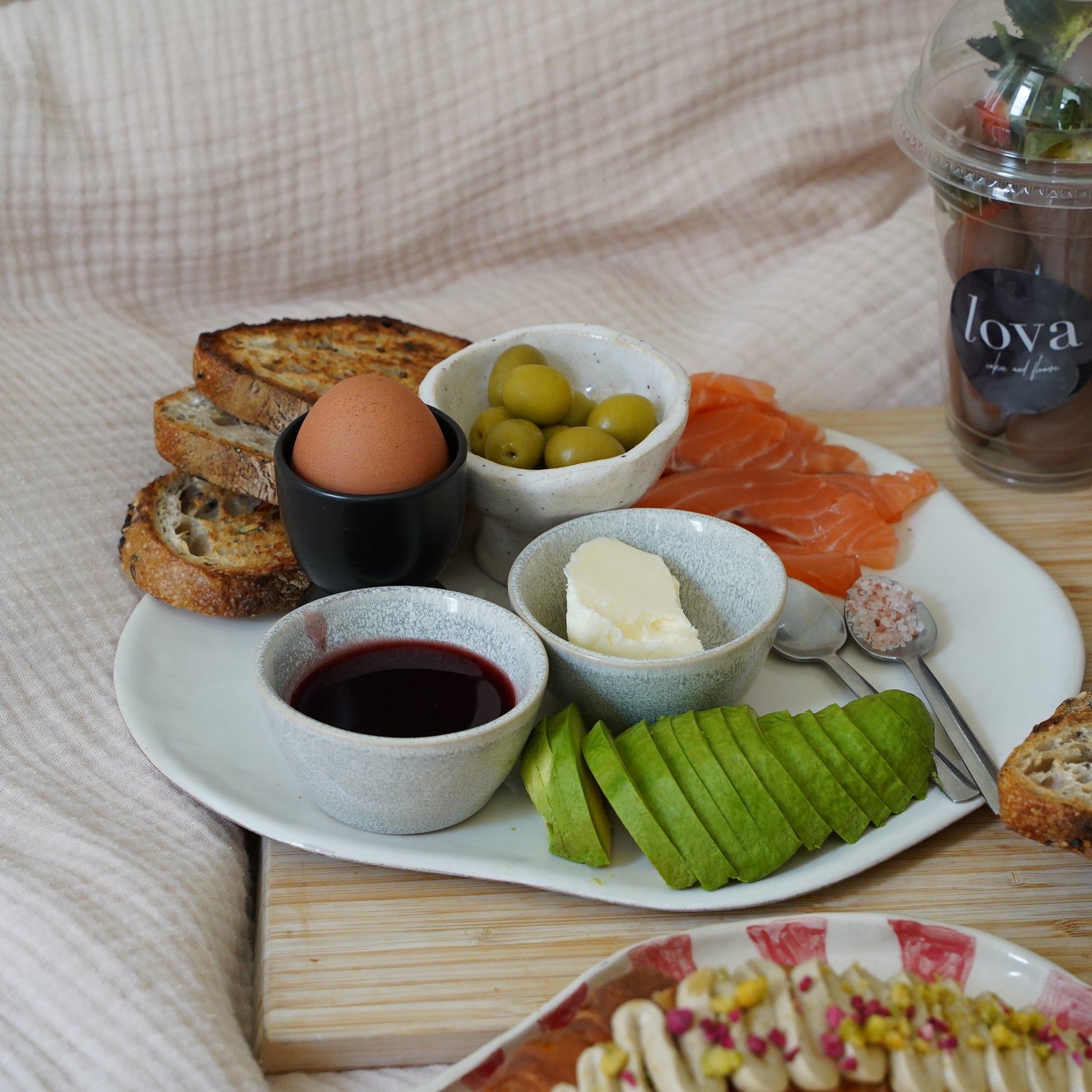 Breakfast spread with eggs, olives, salmon, and bread on a wooden table.
