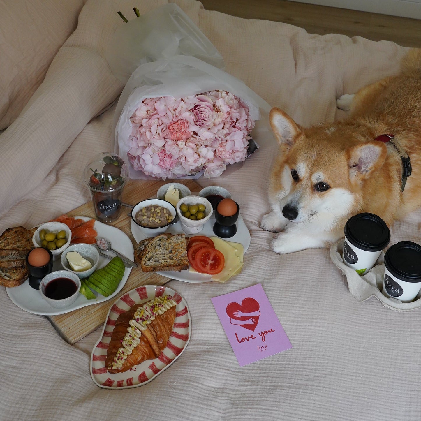 Breakfast in bed set with croissants salmon avocado coffee pink flower bouquet at home, cozy morning delivery Lisbon
