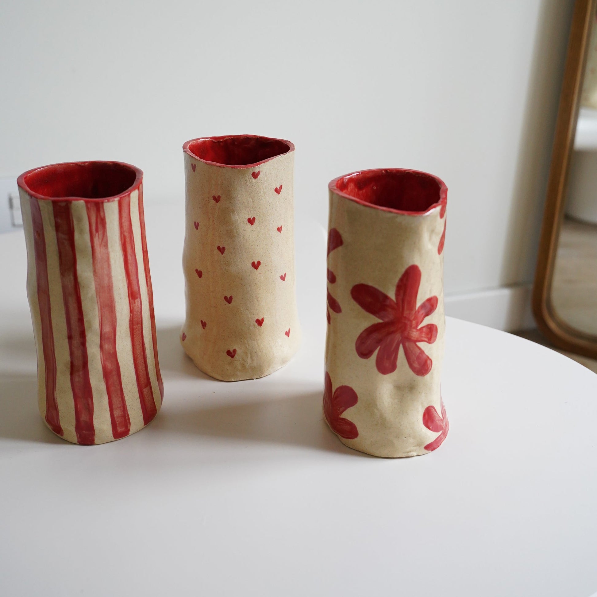 Three cylindrical fabric holders with red accents on a white surface.